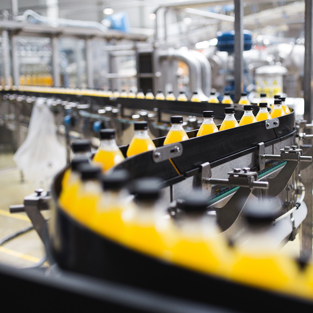 Industrial factory indoors and machinery. Robotic factory line for processing and bottling of soda and orange juice bottles.