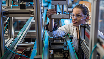 Female engineer examining machine part on a production line.